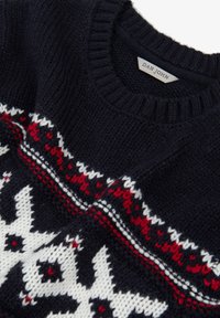 Granatowy sweter robiony na drutach z prążkowanym okrągłym dekoltem, ozdobiony białym i czerwonym geometrycznym wzorem na klatce piersiowej i rękawach. Widoczna metka.