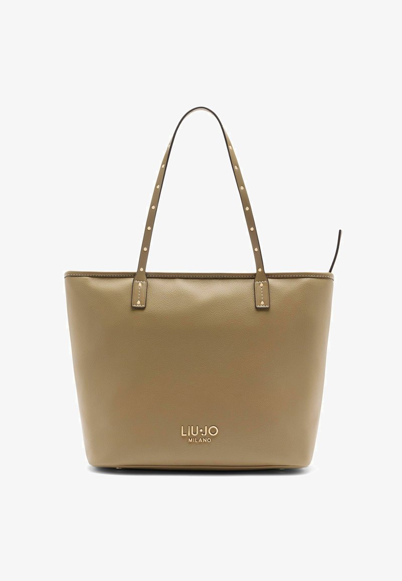 Beżowa skórzana torba typu tote z dwoma paskami na ramię, ozdobiona ćwiekami i wytłoczonym logo na przodzie. Gładka faktura i prostokątny kształt.