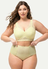 Lichtgele kanten bralette met brede bandjes en golvende randen, gecombineerd met hooggewaisted slips met bloemenpatroon en kantaccenten.