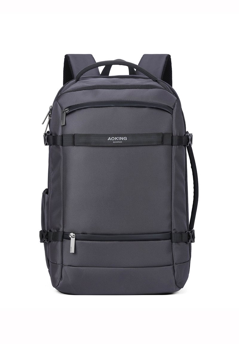 Sac à dos gris avec une surface texturée, plusieurs compartiments zippés, des bretelles ajustables et une poignée supérieure renforcée pour le transport.