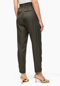Saténové teplákové kalhoty v olivově zelené barvě s elastickým pasem a dvěma zadními kapsami, s volným střihem a manžetami na dolních lemech.