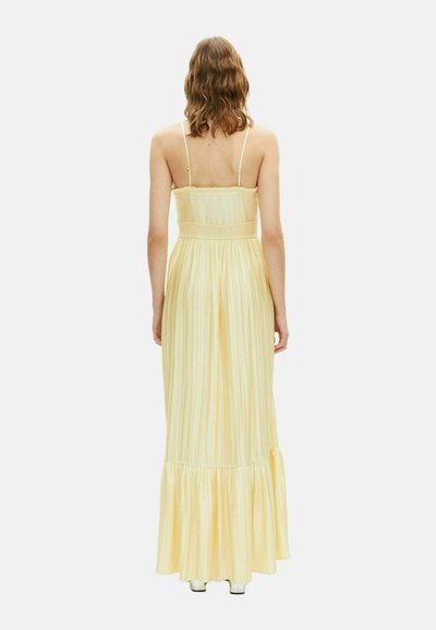 Abito maxi in morbido tessuto giallo chiaro con righe verticali. Presenta spalline regolabili e un orlo a strati.
