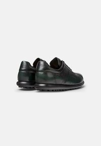 Scarpe in pelle nera con una texture liscia e una tonalità verde. Presentano un punta arrotondata, un colletto imbottito e dettagli testurizzati sui lati.