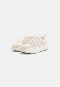 Scarpe da ginnastica beige con una combinazione di suede testurizzato e tomaia in rete, dettagli bianchi e una suola imbottita con un motivo a onda.