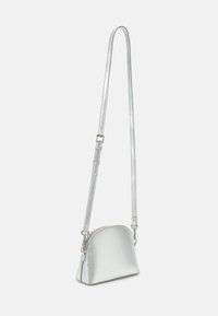 Metallisk silver färgad crossbody-väska med en rundad form, slät yta och justerbar rem. Utrustad med dragkedjestängning och minimalistisk design.