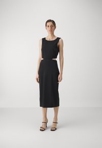 Černý dvoudílný outfit s topem bez rukávů a midi sukni s výřezovými detaily. Vyrobeno z hladké, elastické tkaniny.