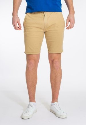 Khaki korte broek van katoen, met een platte voorkant, zijzakken en omgeslagen zoom, gecombineerd met witte sneakers en een blauw T-shirt.