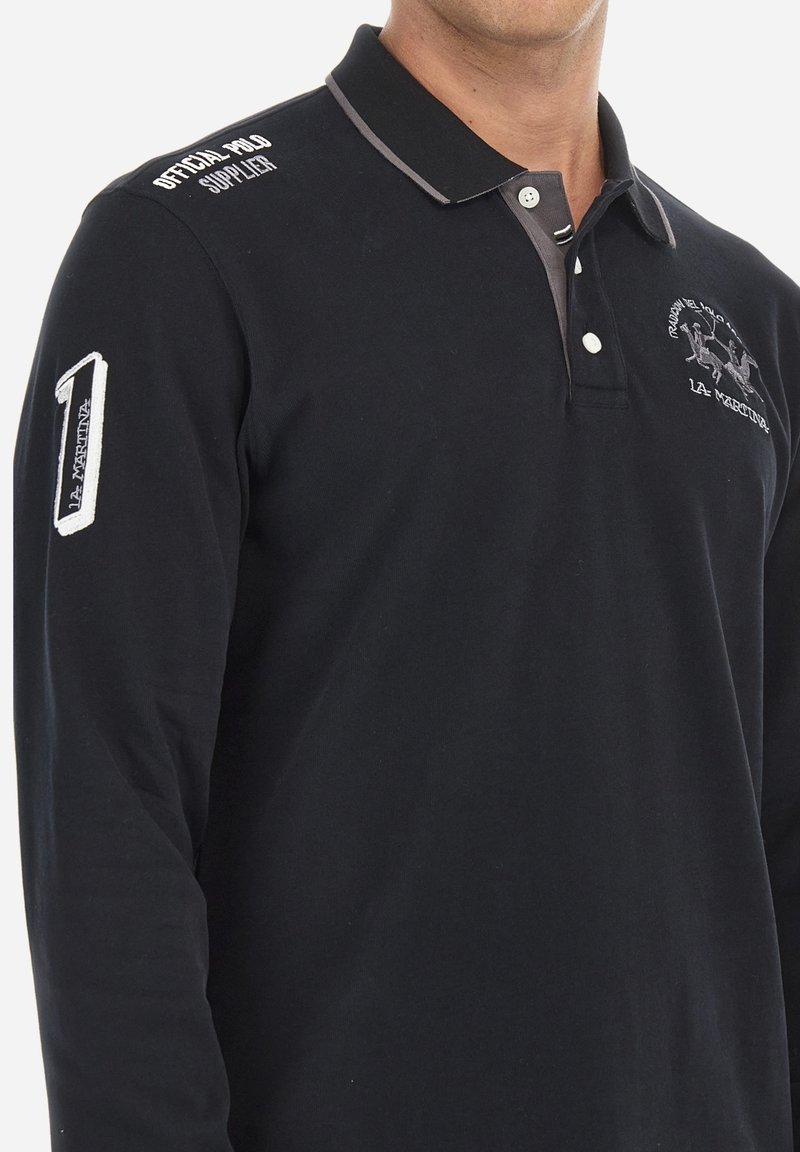 Černá polokošile s dlouhým rukávem a kontrastním límcem. Obsahuje vyšitý logo a číslo "1" na rukávu. Vyrobeno z bavlněné tkaniny.