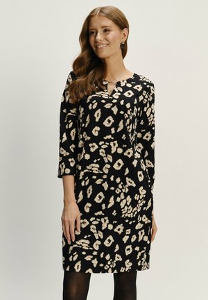Černé šaty s leopardím vzorem v krémové barvě. Mají tříčtvrteční rukávy a malý detail ve tvaru klíčové dírky na krku. Hladká textura látky.
