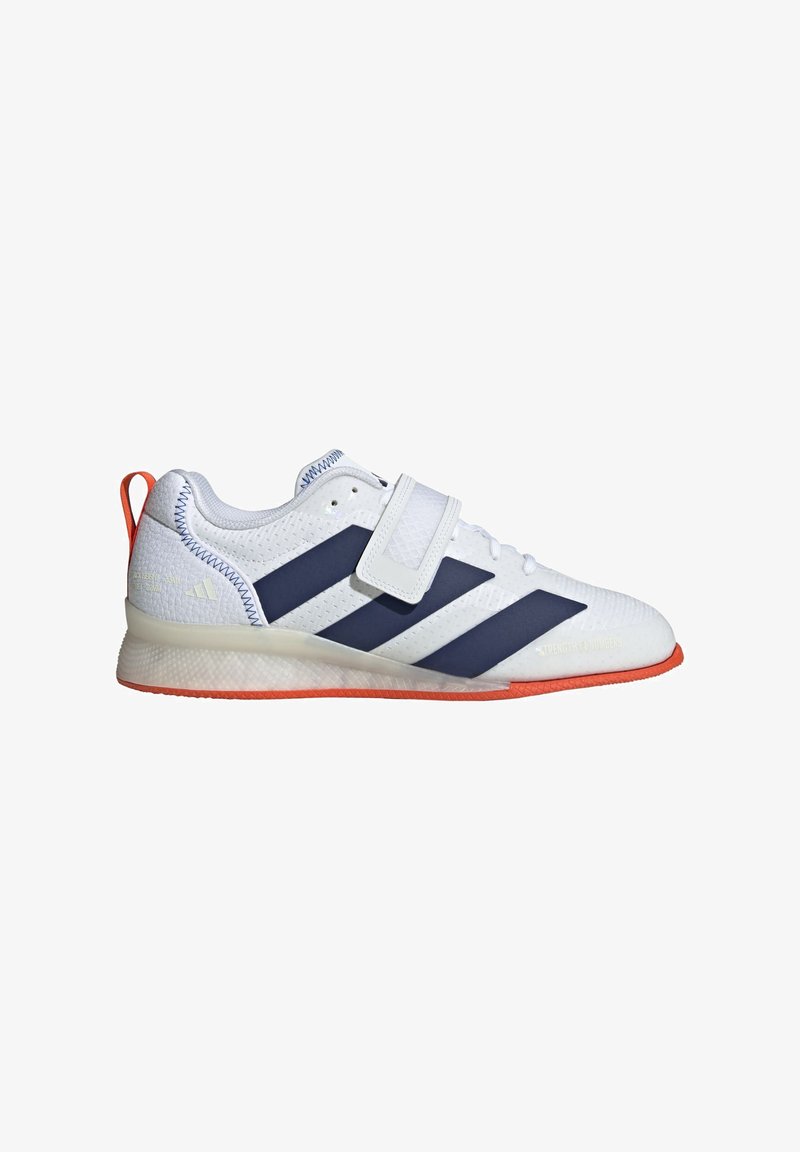 White athletic shoe with navy blue stripes, textured upper, and a hook-and-loop strap. Features an orange rubber outsole.