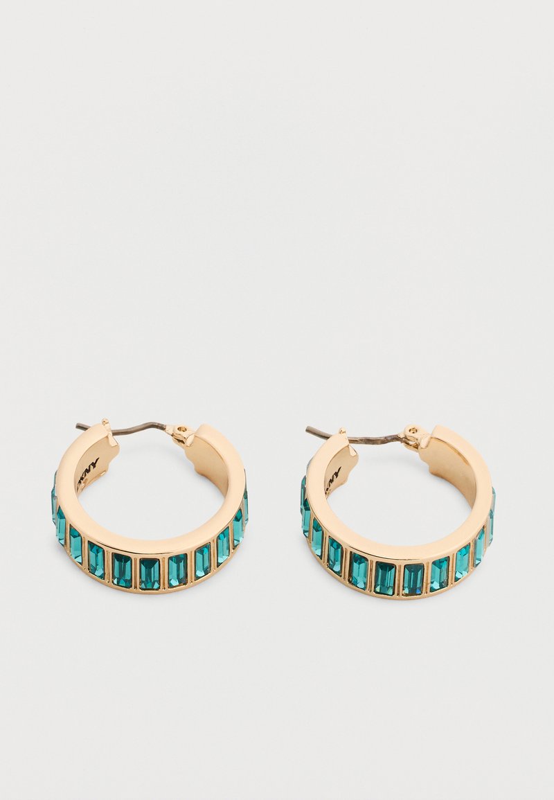 Σκουλαρίκια κρίκοι από χρυσό με ορθογώνιες πέτρες τιρκουάζ τοποθετημένες ομοιόμορφα κατά μήκος της εξωτερικής άκρης, απεικονισμένα πάνω σε ένα απλό ανοιχτό φόντο.