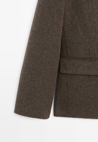 Brun frakke i uldblanding med en tekstureret finish, udstyret med en notch-krave, lange ærmer og en taljelomme. Simpelt, klassisk design.