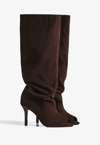 Brown suede knee-high boots with slouchy shaft, pointed toe cutouts, and thin high heels on a white background.