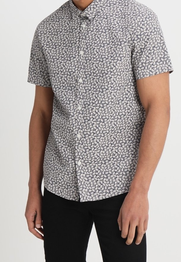 Camicia a maniche corte in tessuto leggero con una piccola stampa floreale blu navy su sfondo crema. Chiusura con bottoni e colletto classico.