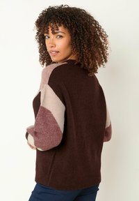 Sweter wełniany z kolorowym wykończeniem w ciemnym brązie, jasnym różu i miękkim beżu. Okrągły dekolt i luźny krój z ściągaczami przy mankietach.