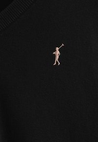 Pull en maille noir avec un design en V. Présente un petit logo brodé de golfeur, de couleur claire, sur la poitrine. Texture douce, coupe classique.