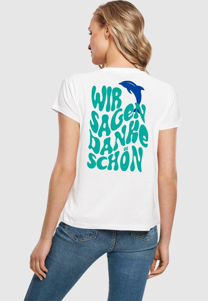 Bílá bavlněná tričko s modrým grafickým designem a textem "WIR SAGEN DANKE SCHÖN" a siluetou delfína na zadní straně.