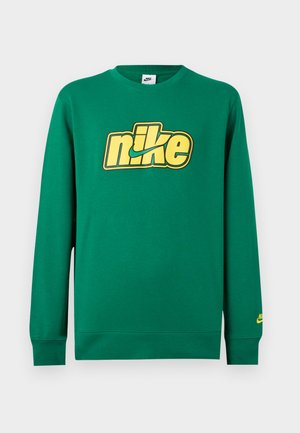 Groene Nike-trui met lange mouwen en gele retrostijl logo op de borst en een klein geel logo op de linkermouwboord.