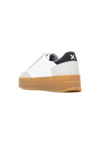 Zapatilla de cuero blanca con acentos de ante gris y talón negro. Presenta una suela de goma y un diseño minimalista.
