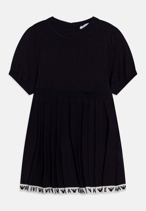 Czarna plisowana sukienka na krótki rękaw z okrągłym dekoltem i białym wykończeniem na dole z powtarzającym się czarnym tekstem.