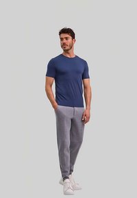 Marineblauw t-shirt met korte mouwen, gecombineerd met lichtgrijze trainingsbroek en witte sneakers. De outfit heeft een eenvoudig design en een comfortabele pasvorm.