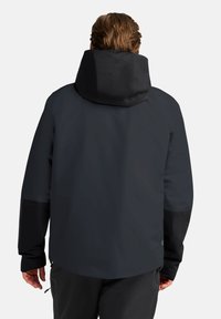 Veste imperméable noire avec capuche, texture lisse et panneaux de manches gris foncé contrastants. Design minimaliste sans logos visibles.