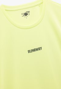Lime vihreä urheilu T-paita, jossa on pyöreä kaulus, tekstuuripinta ja etupuolella mustalla painettuna "RUNAWAY". Koko L.
