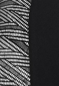 Tela negra con un intrincado patrón de malla blanca por un lado y un textil negro liso por el otro, con diferentes texturas.