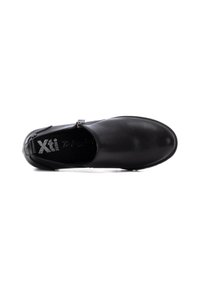 Zapato de cuero negro con textura suave, punta redonda y cinta lateral con hebilla metálica. El interior muestra una plantilla de marca.