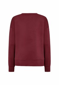 Burgundy-huppari, jossa on pyöreä kaula-aukko, pitkät hihat ja ribbauskiristys. Valmistettu teksturoidusta kankaasta, jossa on suora helma.