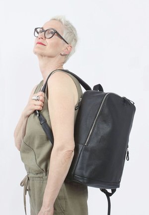 Zaino in pelle nera di forma rettangolare, con chiusura a zip, spallacci regolabili e superficie testurizzata.