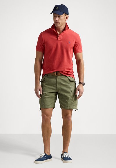 Röd pikétröja med krage, olivgröna cargo-shorts, marinblå keps och marinblå kanvas-skor. Avslappnad outfit med en bekväm passform och praktisk design.