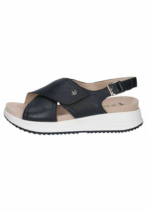 Sandales à bout ouvert en cuir texturé bleu marine, avec une large bande croisée, une bride réglable à la cheville et une semelle blanche texturée.