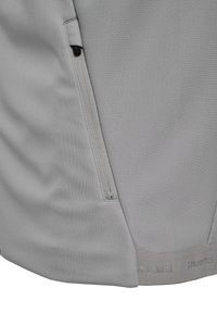 Graue Sportshorts mit glatter Textur, ausgestattet mit einer seitlichen Reißverschlusstasche und einem Markenlogo am Saum.