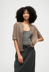 Short-sleeve brown cardigan in soft material with button closure, worn over a gray tank top, paired with a dark gray skirt.