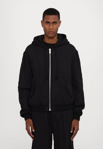 Chaqueta bomber de lino negra con cremallera frontal, capucha ajustable y puños acanalados. Presenta bolsillos frontales y un ajuste relajado.