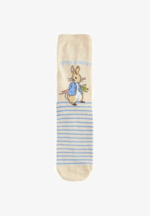 Beige Socke mit hellblauen Streifen und einer Illustration von Peter Hase, der eine blaue Jacke trägt und Gemüse hält, mit dem Text "Peter Hase" darüber.