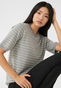 Gråstribet skjorte med korte ærmer lavet af blødt stof, med rund halsudskæring og glat tekstur, kombineret med sorte bukser.