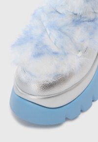 Flauschiger blauer und weißer Sneaker mit einer metallisch silbernen Zehenkappe, dickem blauen Sohlenrand und strukturiertem Obermaterial für ein einzigartiges Design.
