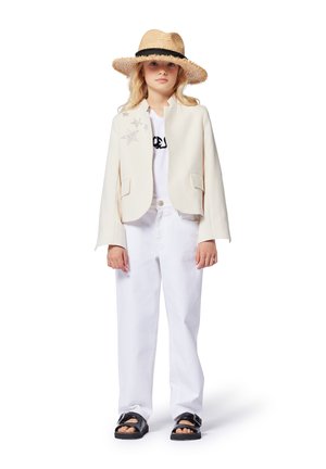 Blazer crème avec des embellissements en étoiles, t-shirt blanc, pantalon blanc, sandales noires et un chapeau en paille avec un ruban noir.