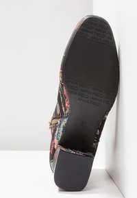 Semelle de bottine noire à motif floral avec "ANNA FIELD" embossé sur la bande de roulement, fermeture éclair visible sur le côté et talon bloc, taille 37.