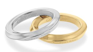 Anillos entrelazados de plata y oro con un acabado suave. Ambos presentan el texto grabado "Calvin Klein" en el interior de las bandas.