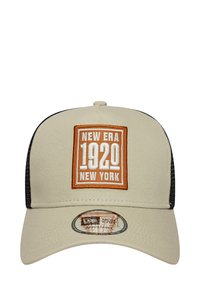Beige Baseballkappe mit schwarzem Netzrücken, ausgestattet mit einem orange-weißen Patch mit der Aufschrift "New Era 1920 New York" und einem verstellbaren Aufkleber auf dem Schirm.