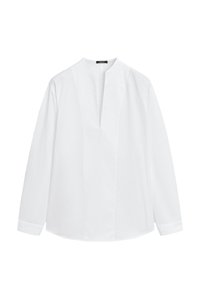 Blouse blanche à manches longues avec un col sans col et une fente à l'avant, présentée sur un fond blanc uni.