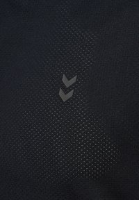 Zwart sportstof met een gestructureerd, gestippeld patroon. Heeft een grijze chevronlogo, een subtiele glans en een nauwsluitend design.
