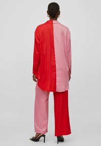 Set di camicia e pantaloni in seta con design a blocchi di colore, caratterizzato da toni di rosso e rosa, vestibilità rilassata, maniche lunghe e una texture liscia.