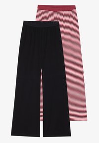 Kaksi paria leveälahkeisia housuja: toiset täysin mustat, joissa on sileä pinta, ja toiset punavalkoisilla pystysuorilla raidoilla, joissa on joustavat vyötärönauhat.