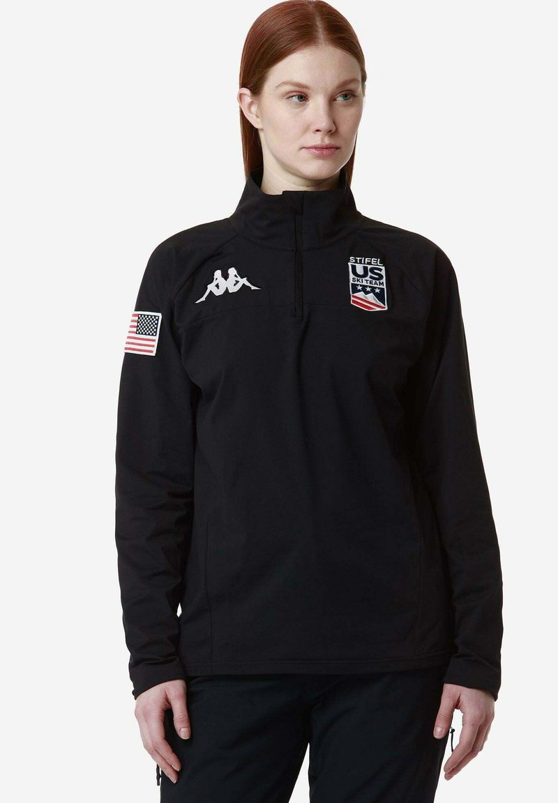 Pullover nero con zip a quarti, logo Kappa sul petto, patch con bandiera degli Stati Uniti sulla manica e emblema "Stifel US Ski Team"; realizzato in un tessuto morbido e flessibile.
