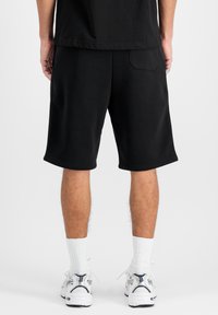  Sorte bomulds shorts med en afslappet pasform, præget kant og en baglomme. Sammen med hvide ankelstrømper og sportssko.