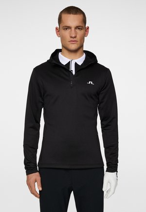 Schwarzer Langarmpullover mit einem Reißverschluss im Mock-Neck-Stil, aus glattem Stoff gefertigt. Verfügt über eine Kapuze und ein weißes Logo auf der Brust.